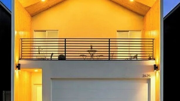 Une maison moderne à deux étages, dotée d’un garage, d’un balcon et d’une entrée bien éclairée.