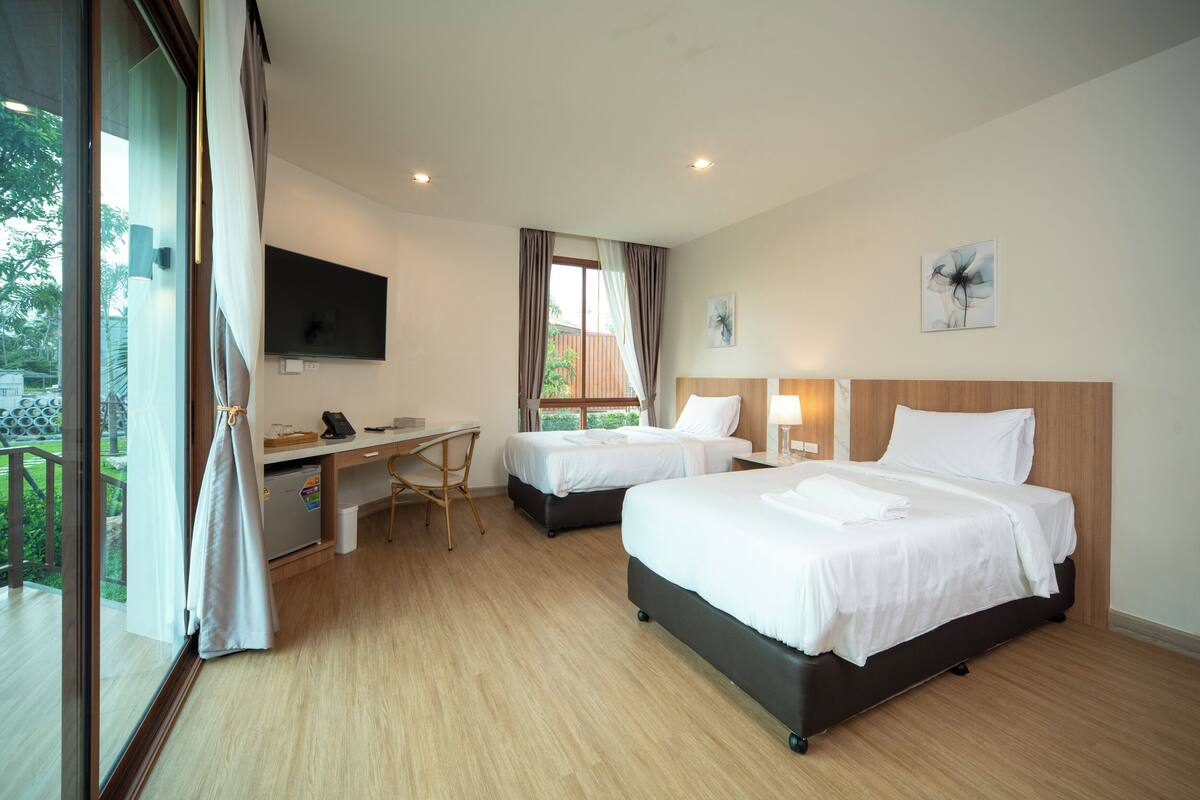 A hotel room with two beds, a desk, and a TV.