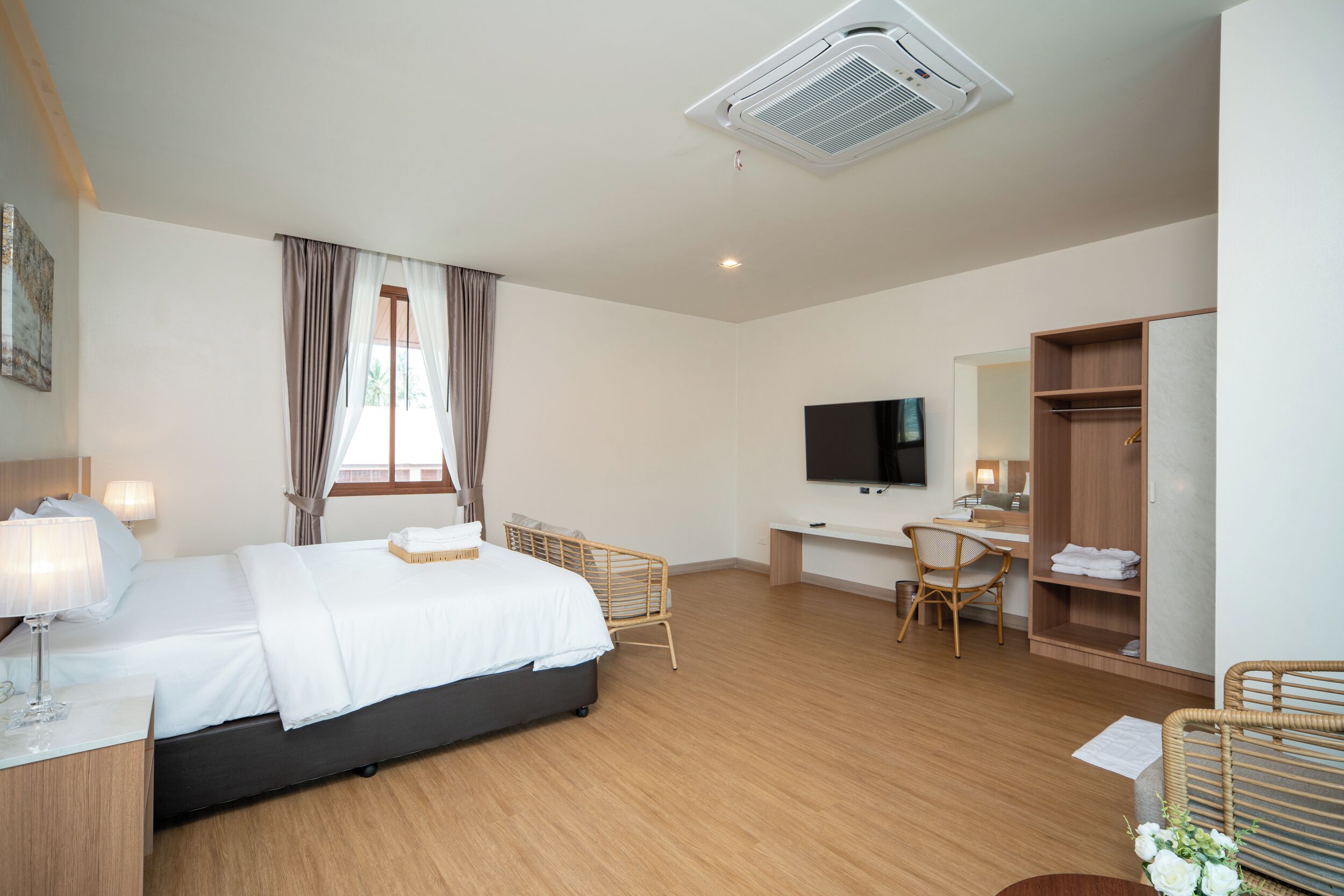 Habitación de hotel con cama, escritorio, televisión, armario y ventana con cortinas.