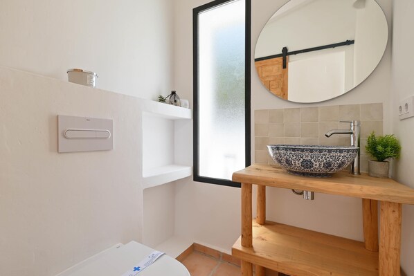 Une salle de bain moderne avec un meuble-lavabo en bois, un grand miroir et un lavabo décoratif en forme de bol.