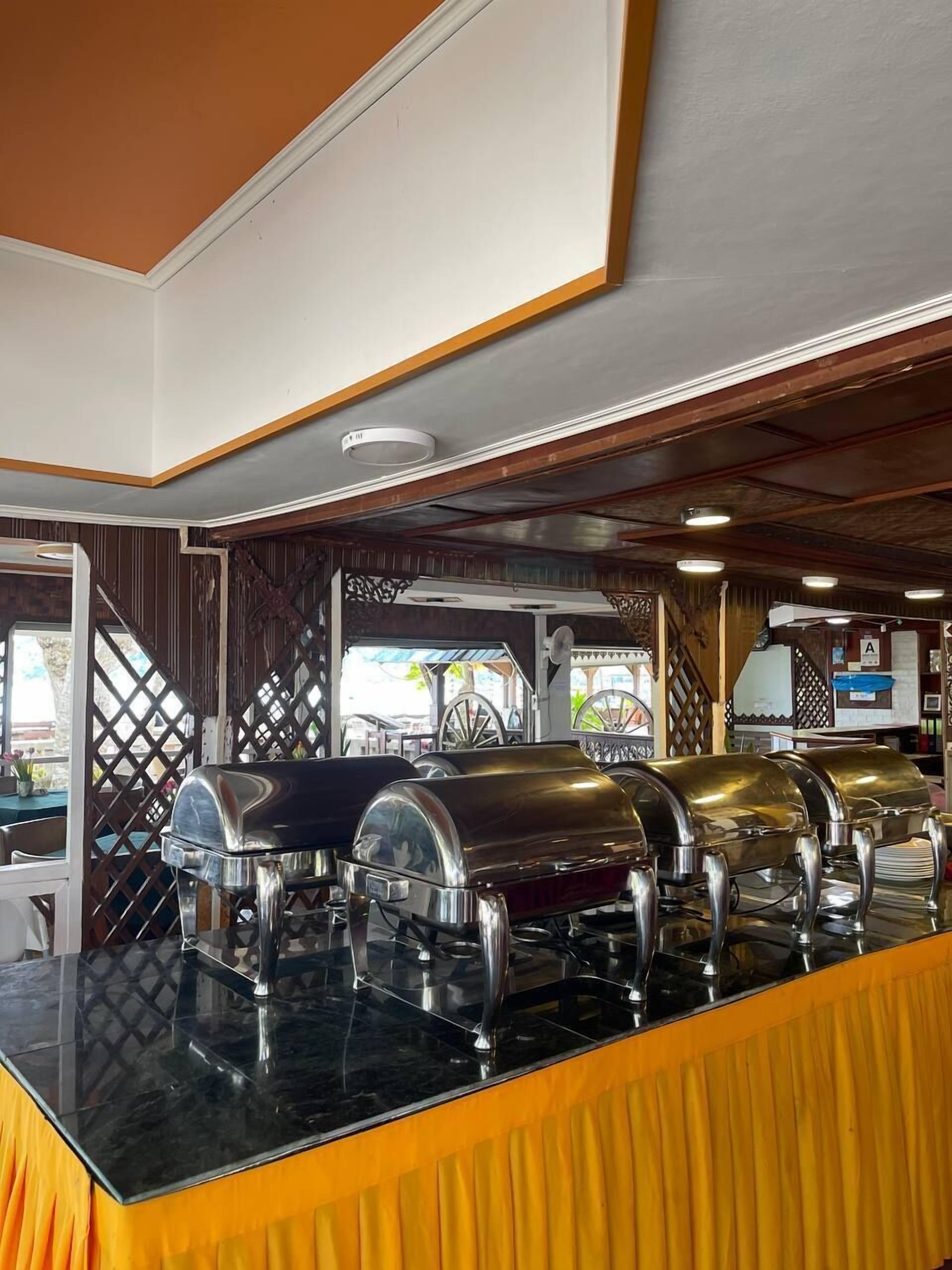 A buffet area with multiple self-service food stations, a wooden ceiling, and a view of the outdoor seating area.