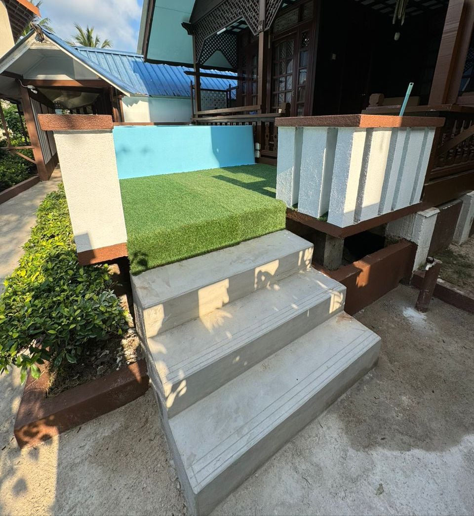 A concrete staircase leading to a porch with a blue wall and a small garden area.
