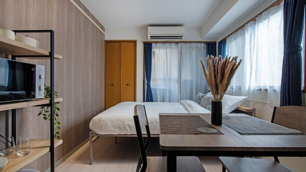 Una moderna camera d'albergo con un letto, una scrivania con una sedia, una TV e una pianta.