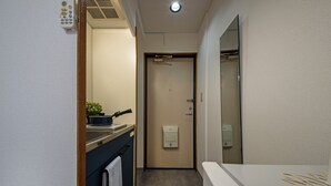 Un couloir étroit avec un lavabo, un porte-serviettes et une porte donnant sur une salle de bain.