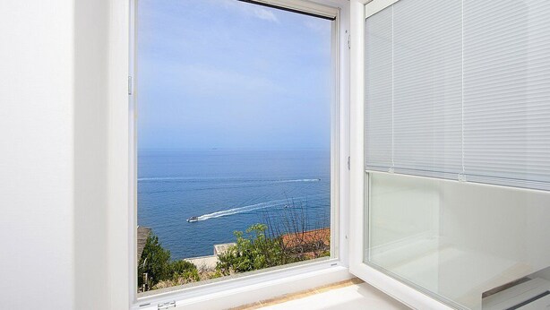 Una habitación con un ventanal grande con vistas al mar, una pared blanca y una puerta corredera cerrada.