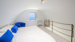 Un dormitorio con cama, una silla, un ventanal y una barrera de cuerda.