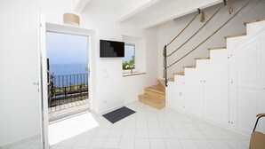 Una habitación amplia con balcón, escalera y televisión.