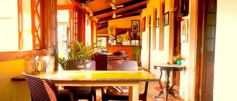 A cozy dining area with a wooden table and chairs, a small side table, and a potted plant.