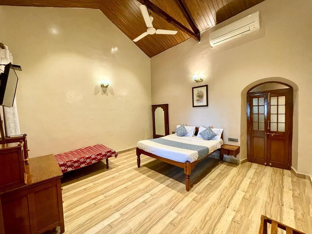 Une chambre à coucher avec un lit en bois, un banc, un miroir et une porte.