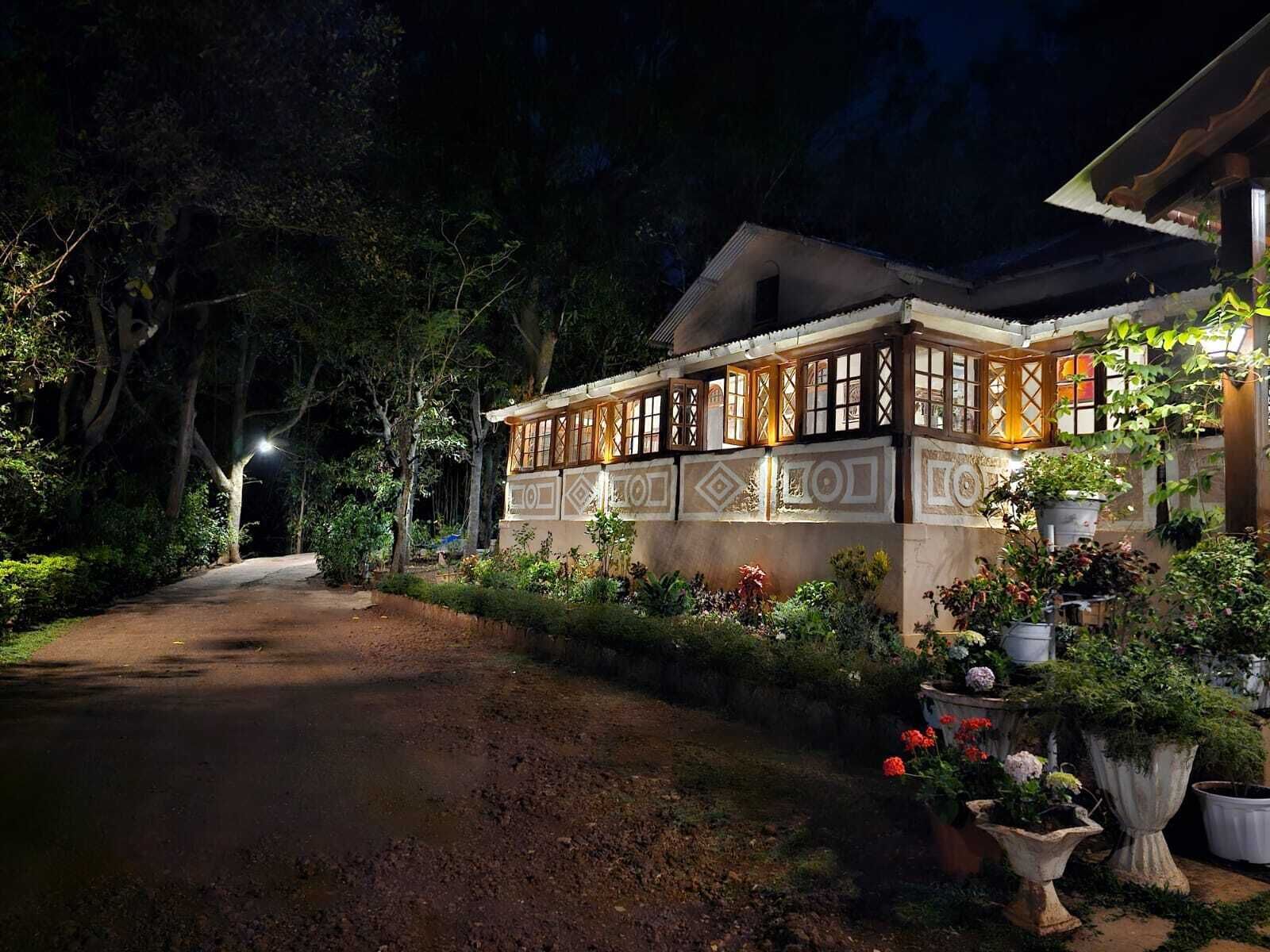 A traditional building with a tiled facade, a covered walkway, and a garden with potted plants and flowers.