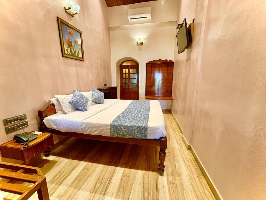 A bedroom with a wooden bed, a nightstand, a desk, and a chair.