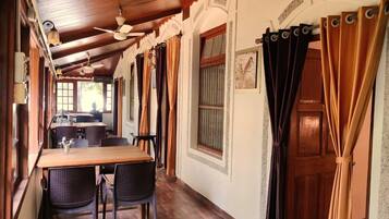A dining area with a wooden table and chairs, a ceiling fan, and a view of the kitchen in the background.