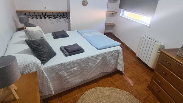Une chambre à coucher comprenant un lit, des tables de chevet, une commode, un radiateur et des éléments décoratifs muraux.
