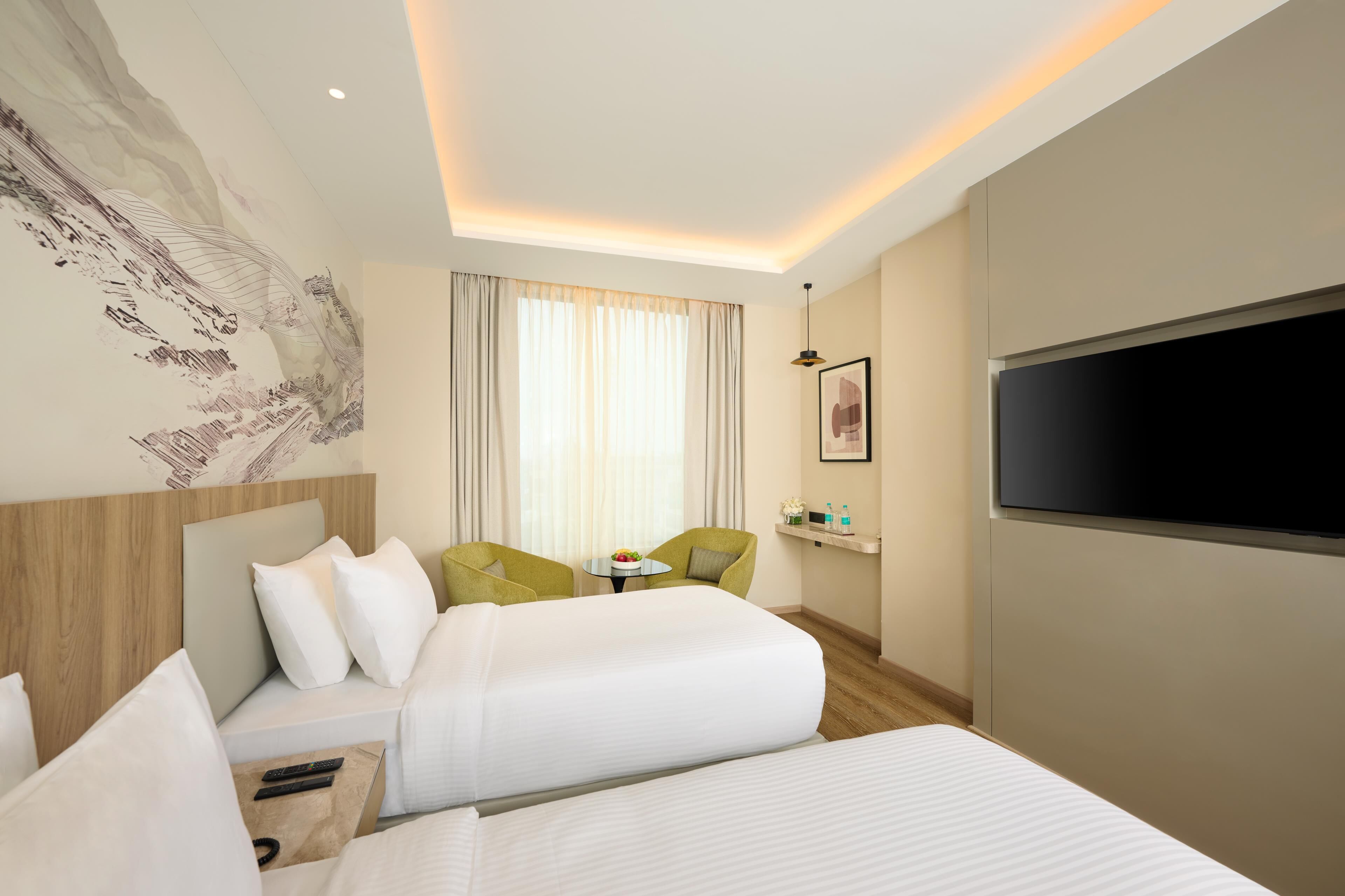 Een hotelkamer met twee bedden, een bureau, een stoel, een televisie en een schilderij aan de muur.