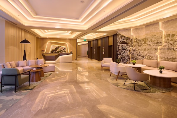 A modern lobby with a reception desk, sofas, and a large wall map.