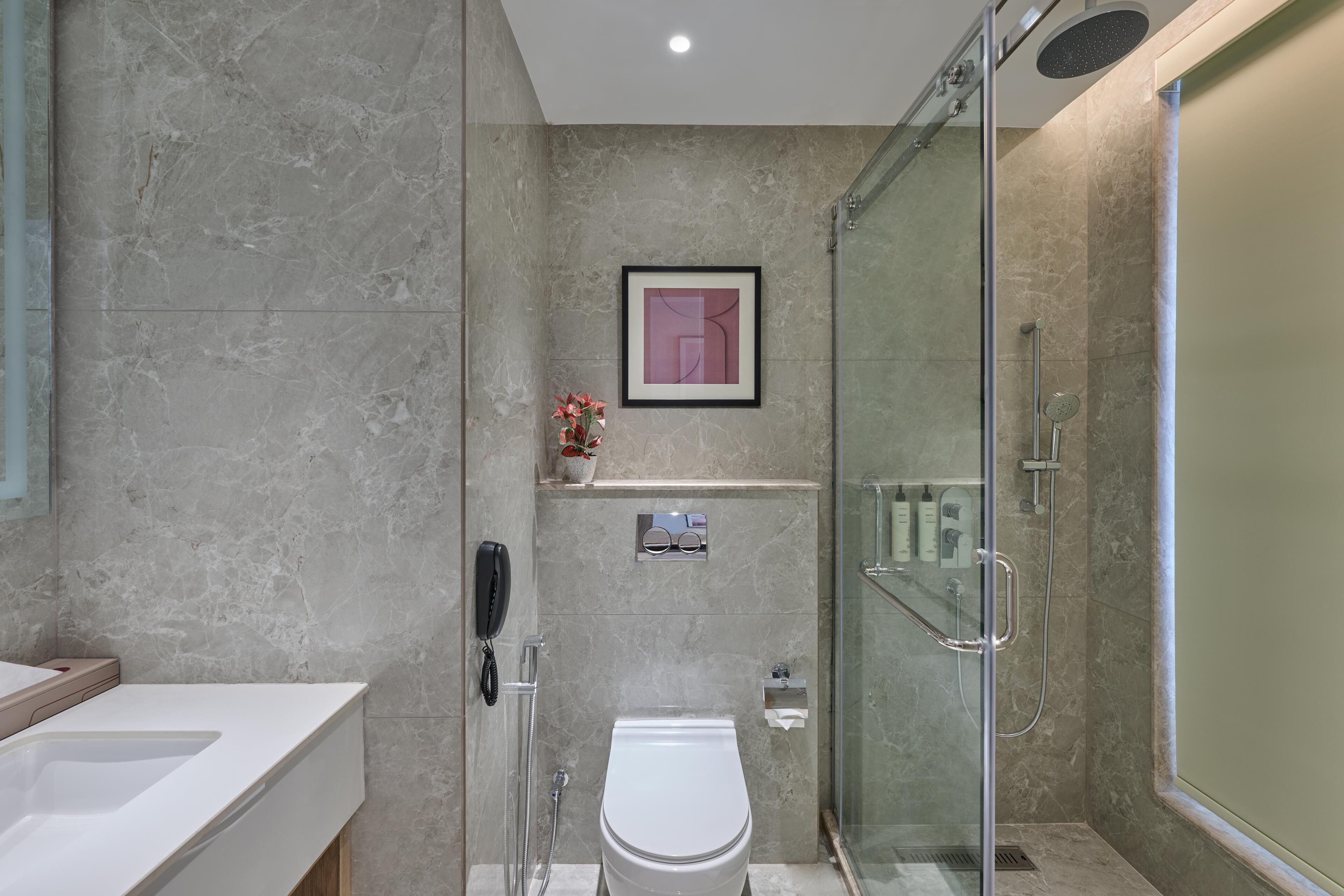 Un baño moderno con ducha envuelta en vidrio, inodoro y tocador con lavabo.