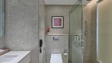 Un baño moderno con ducha envuelta en vidrio, inodoro y tocador con lavabo.
