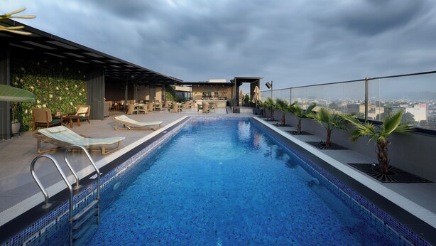 A rooftop pool with lounge chairs and a bar area, overlooking a cityscape. - Riviera Sarovar Portico Pathankot (Pathankot)