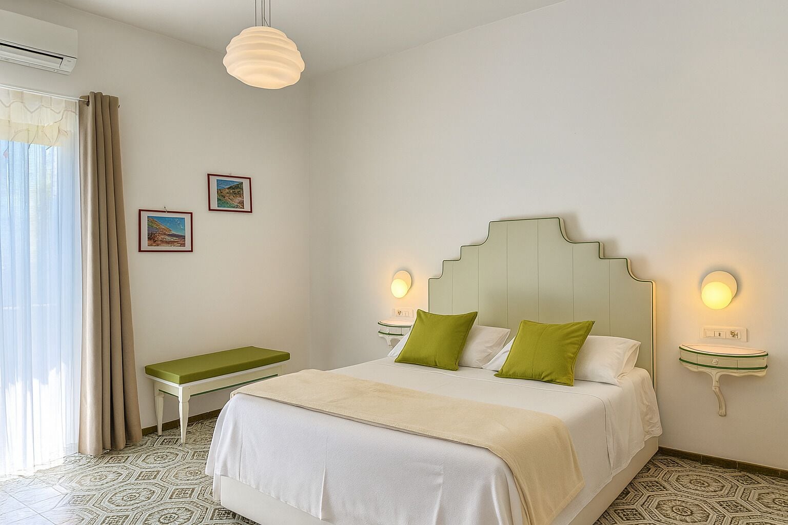 Une chambre à coucher comprenant un lit, des tables de chevet, un banc, un tableau au mur et un appareil de climatisation.