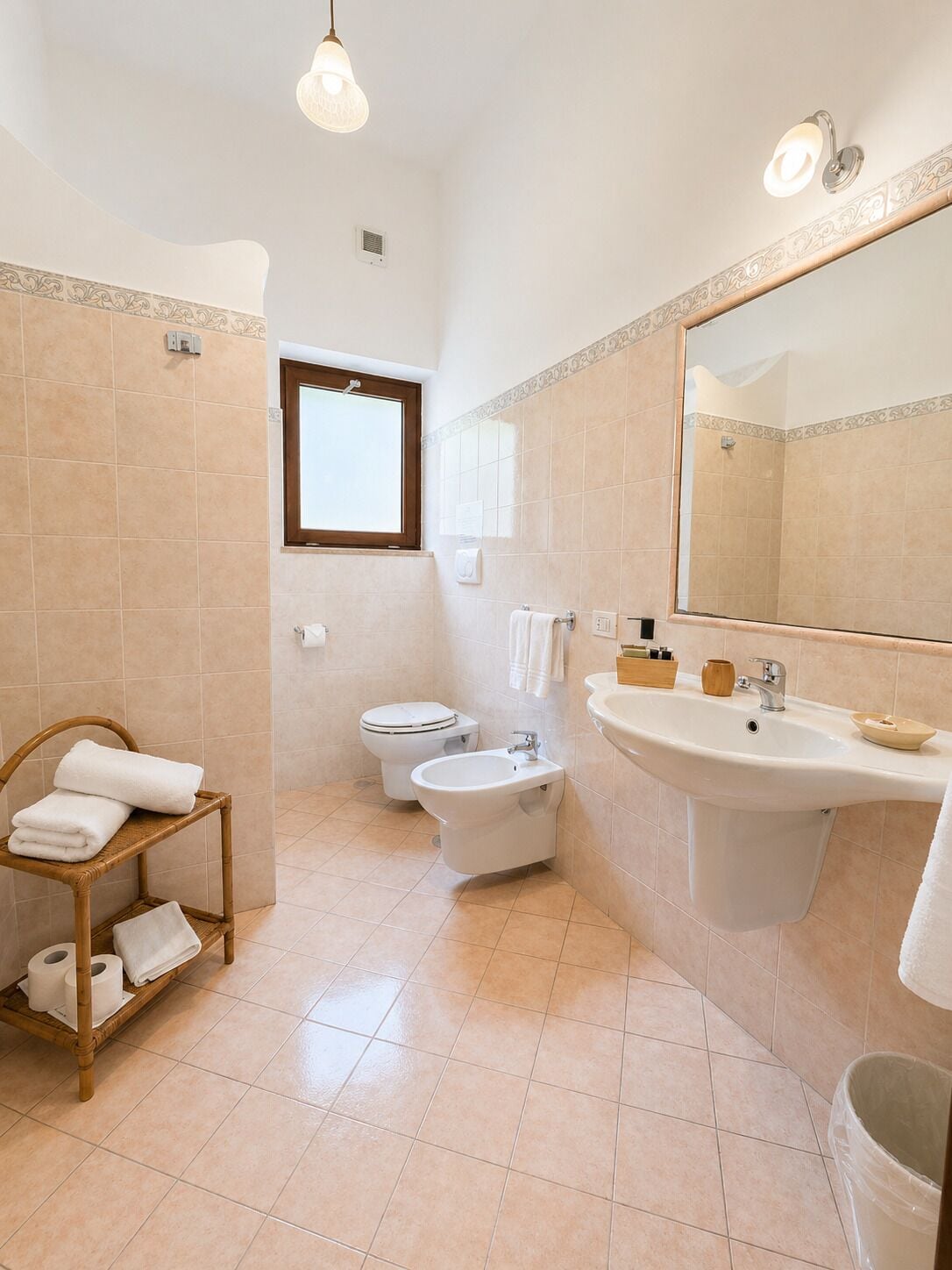 A bathroom with a toilet, bidet, sink, and a mirror.