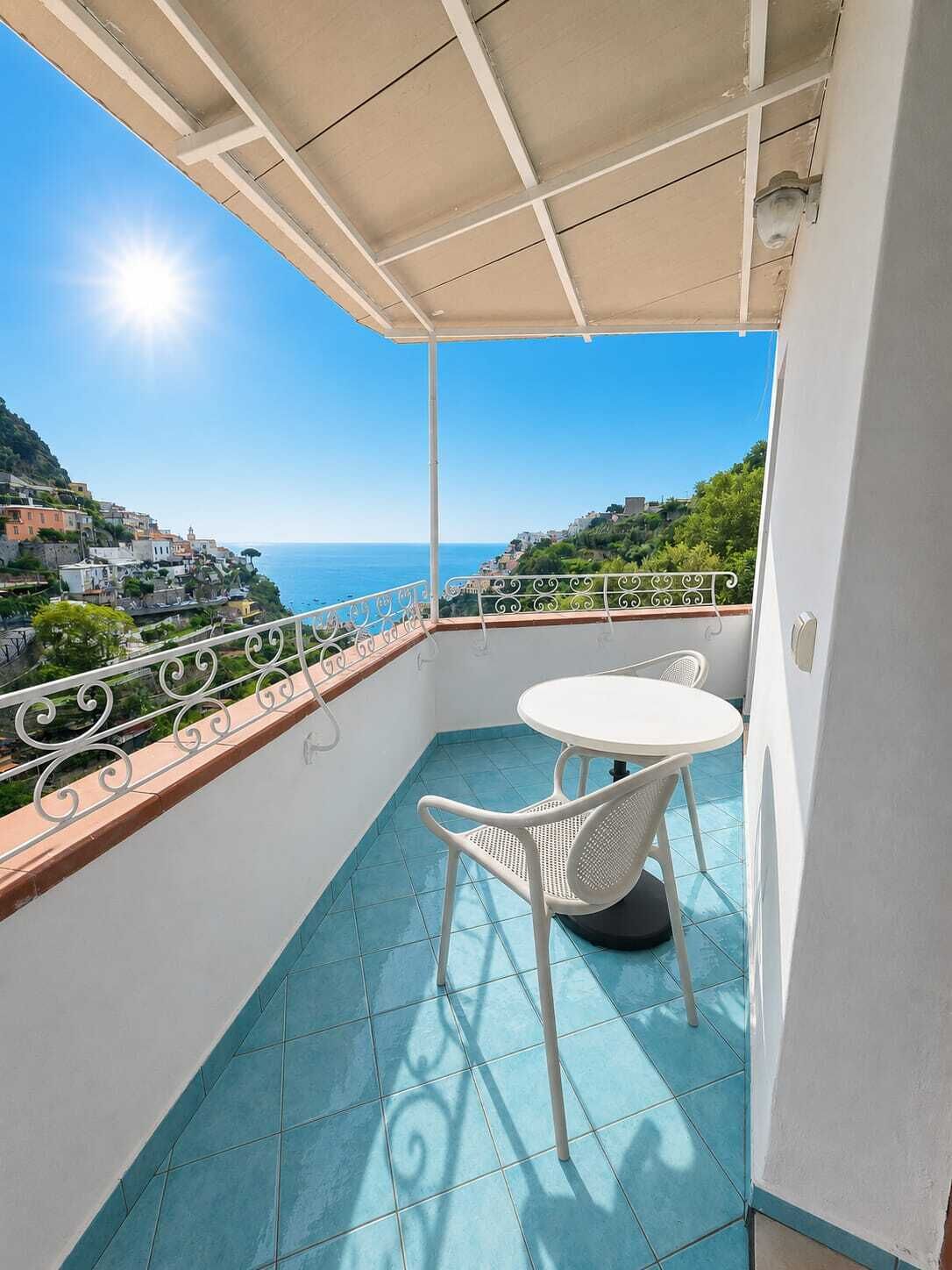 Ein Balkon mit Tisch und Stühlen, Blick auf das Meer und ein Fliesenboden.