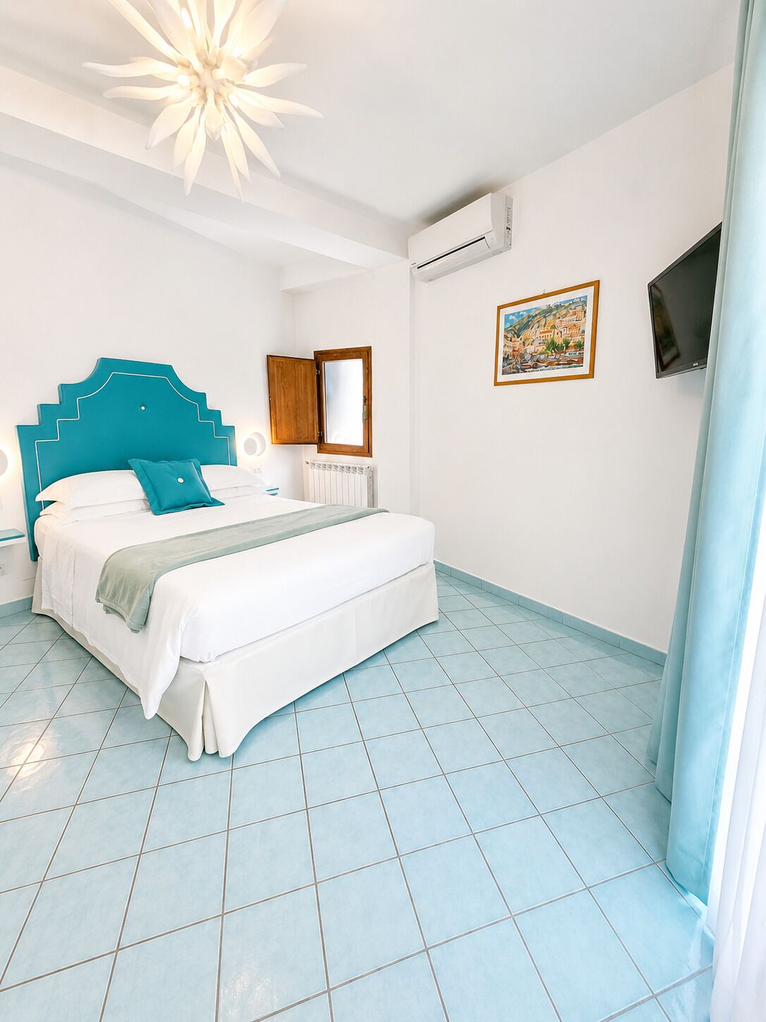 Une chambre à coucher comprenant un lit, une table de chevet, une commode, une fenêtre, un appareil de climatisation, un tableau et un téléviseur.