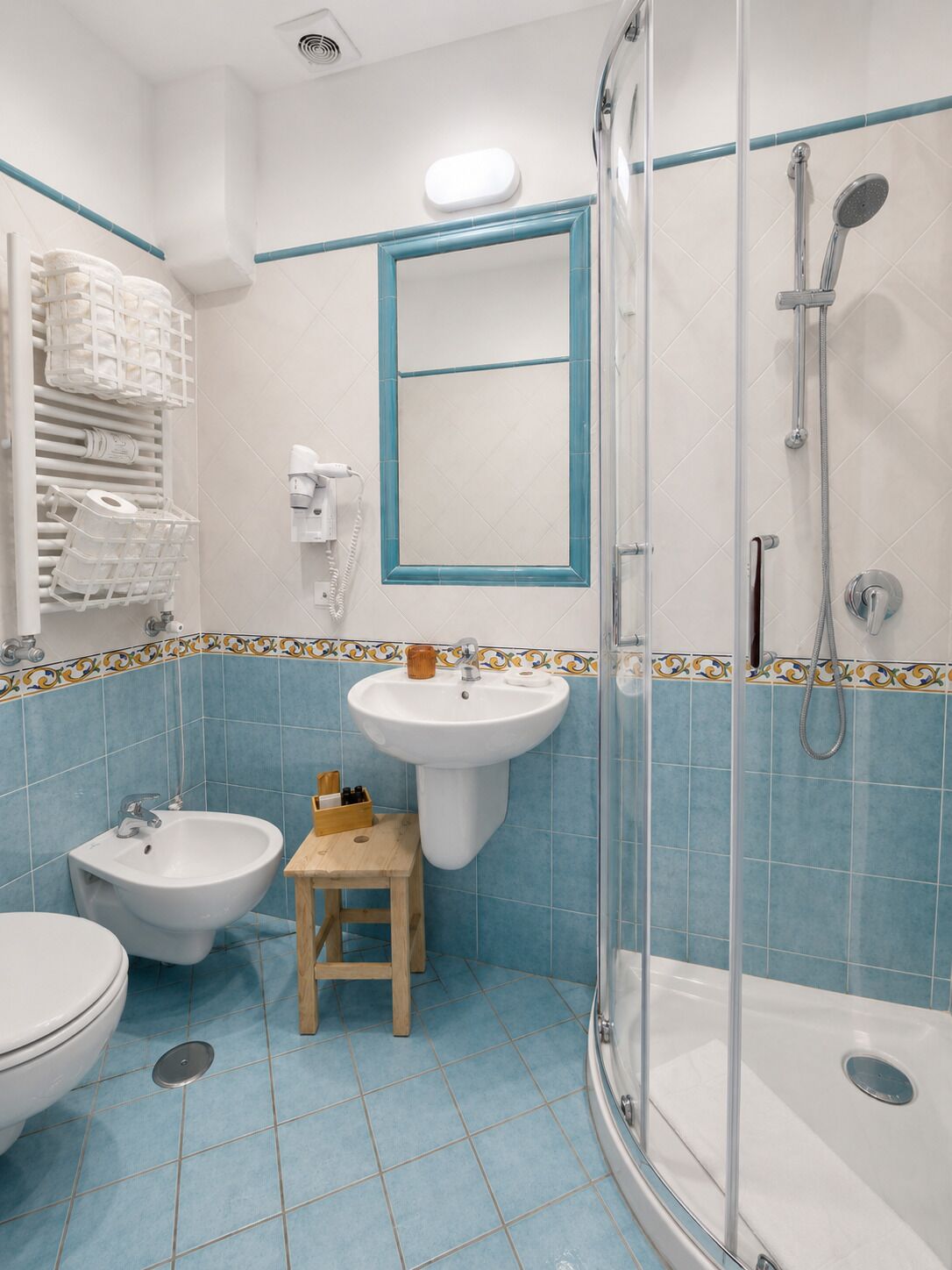 Een badkamer met een douche, twee wasbakken, een toilet en een bidet.