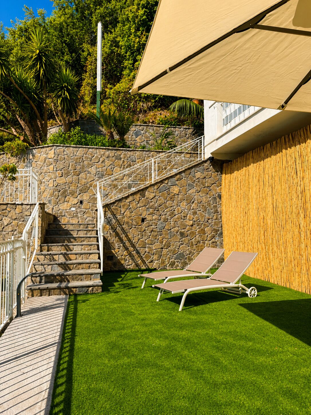Un escalier en pierre menant à un balcon agrémenté de deux fauteuils et d’une pergola.