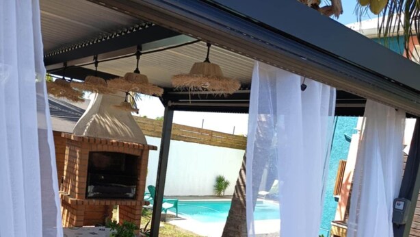 Un espace extérieur abrité, aménagé avec une table, des chaises et un barbecue.