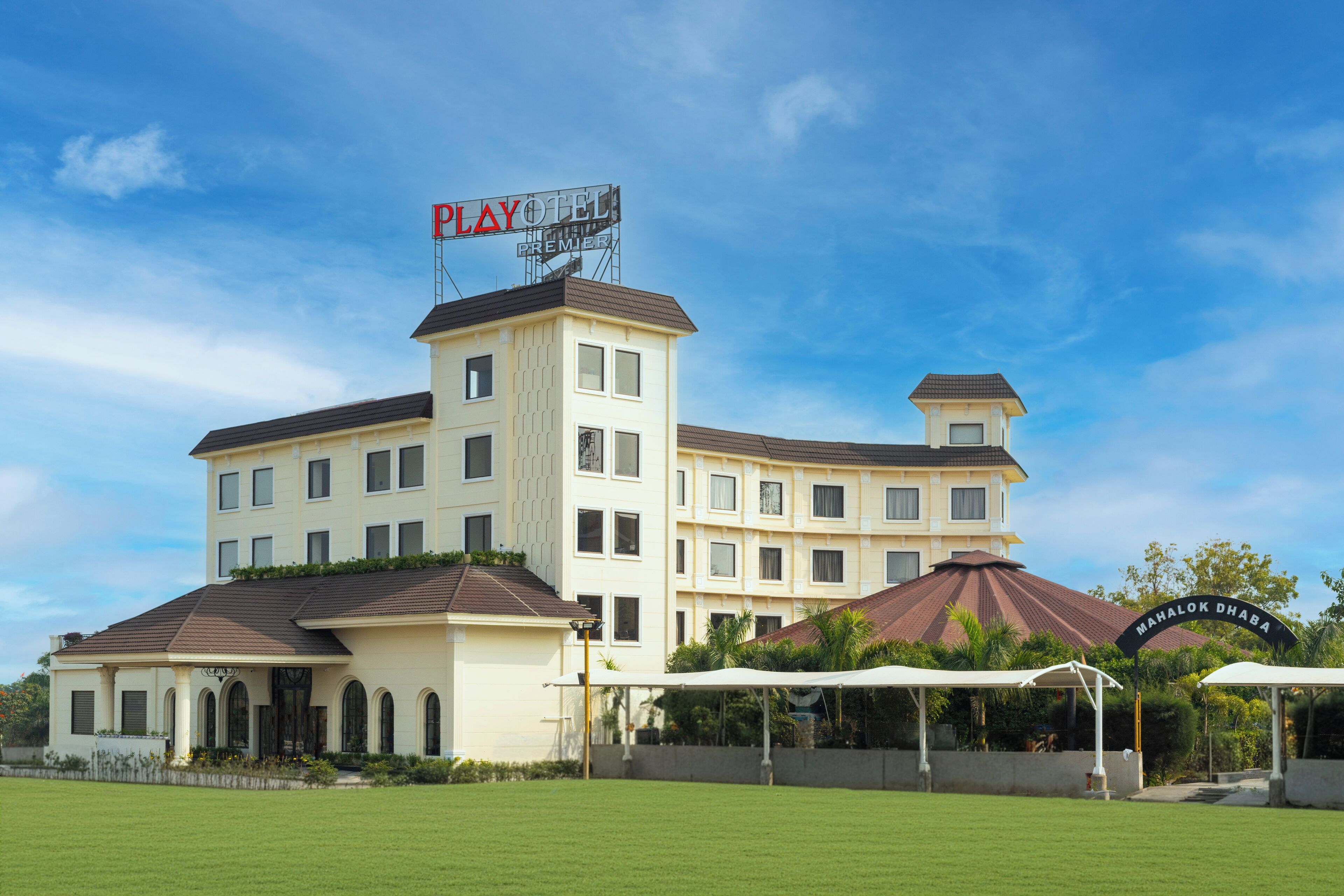 A hotel with a Playtex sign, multiple balconies, and a sign for Mahalok Dhaba.