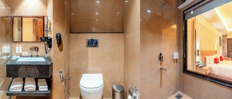 Un baño moderno con tocador de mármol, inodoro, ducha y un espejo grande.