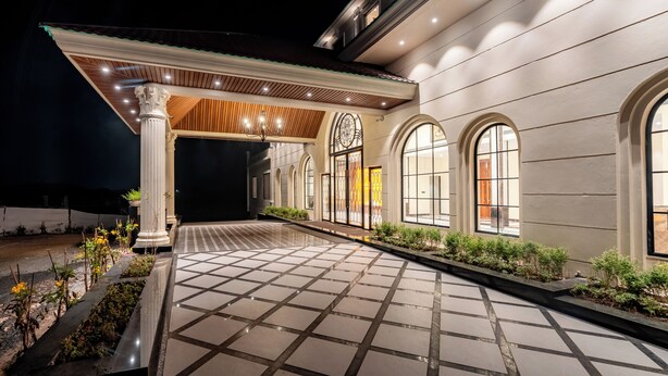 A well-lit building entrance with a tiled pathway, columns, and arched windows. - Playotel Premier Ujjain (Ujjain)