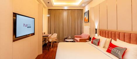 A hotel room with a bed, a desk, a chair, a TV, and a curtain.