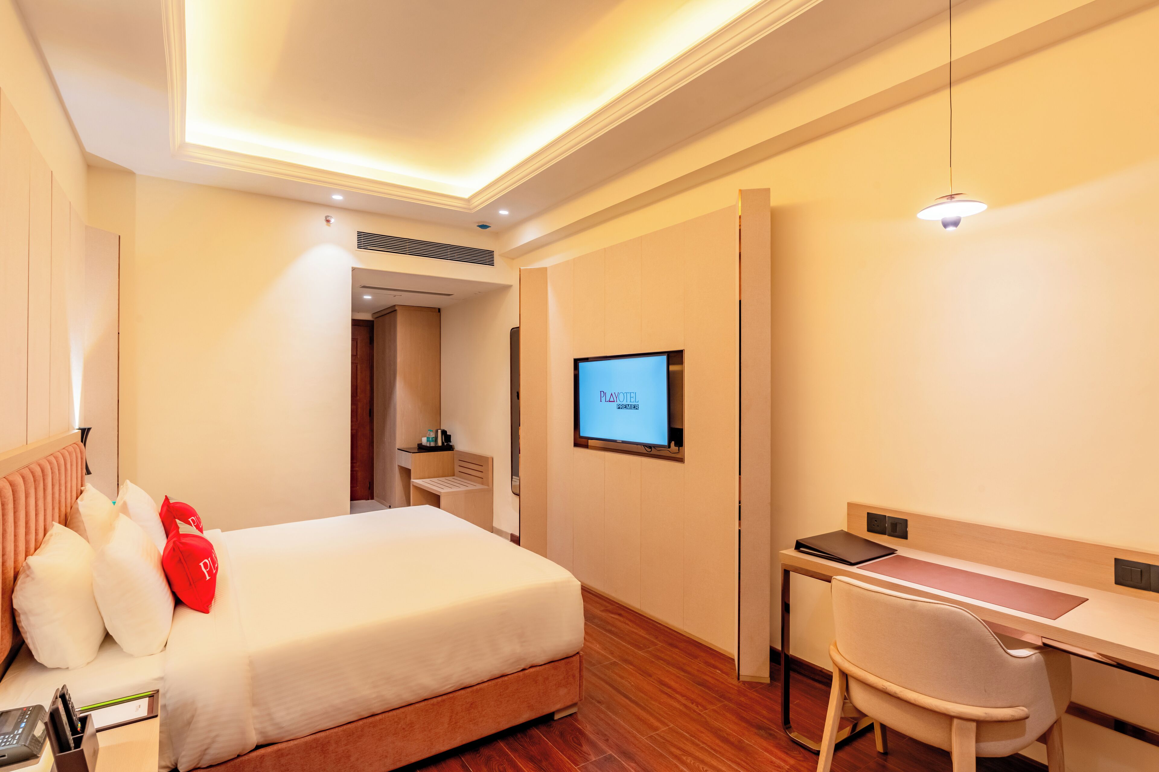 Ein Hotelzimmer mit einem Bett, einem Schreibtisch und einem Fernseher, der 'PLAYOFT' anzeigt.