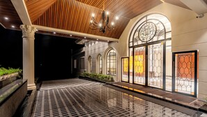 A spacious atrium with a reflective tiled floor, a wooden ceiling, and a large arched window with decorative glass panels. - Playotel Premier Ujjain (Ujjain)