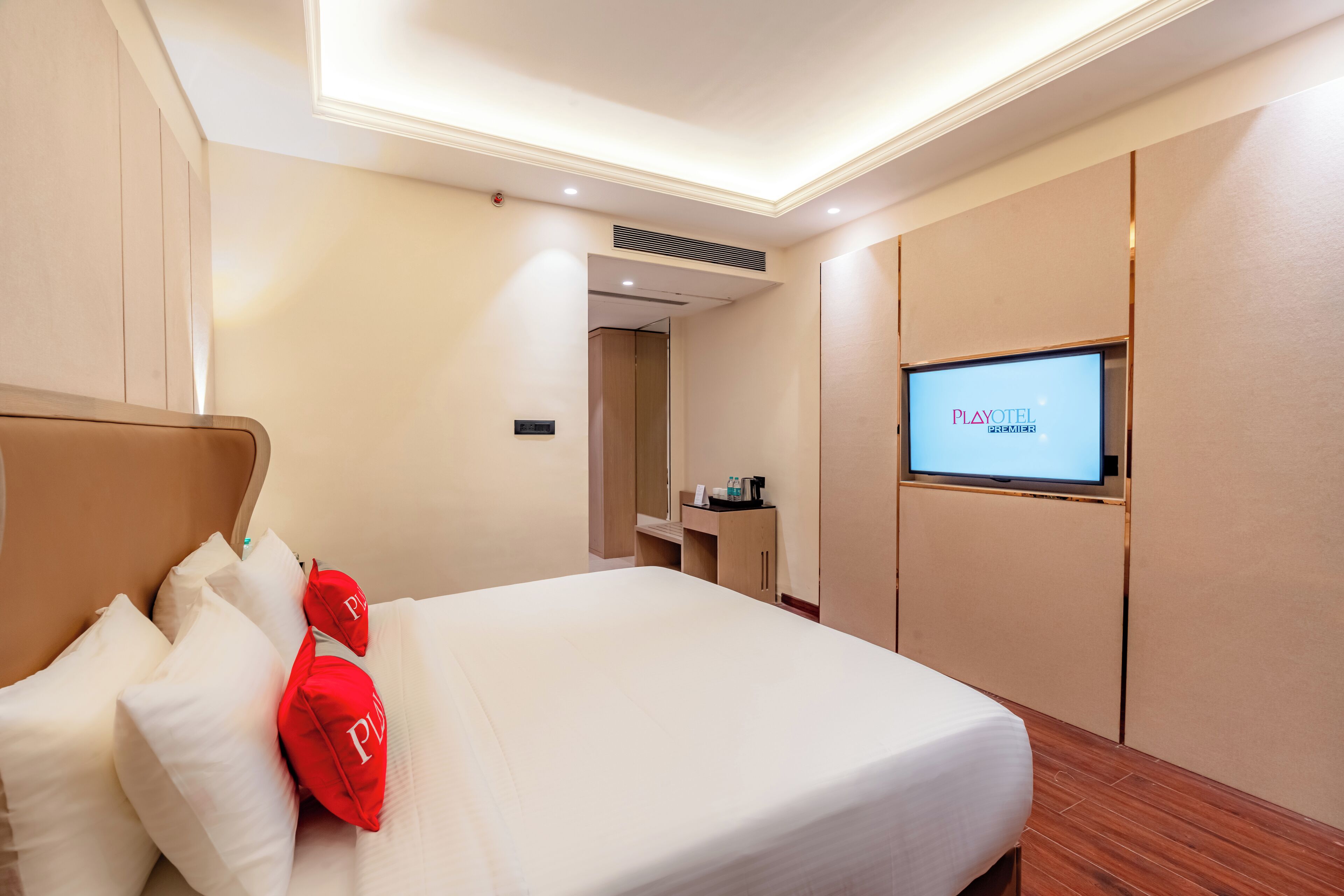 Una habitación de hotel con una cama, un televisor en la pared y un escritorio con una silla.