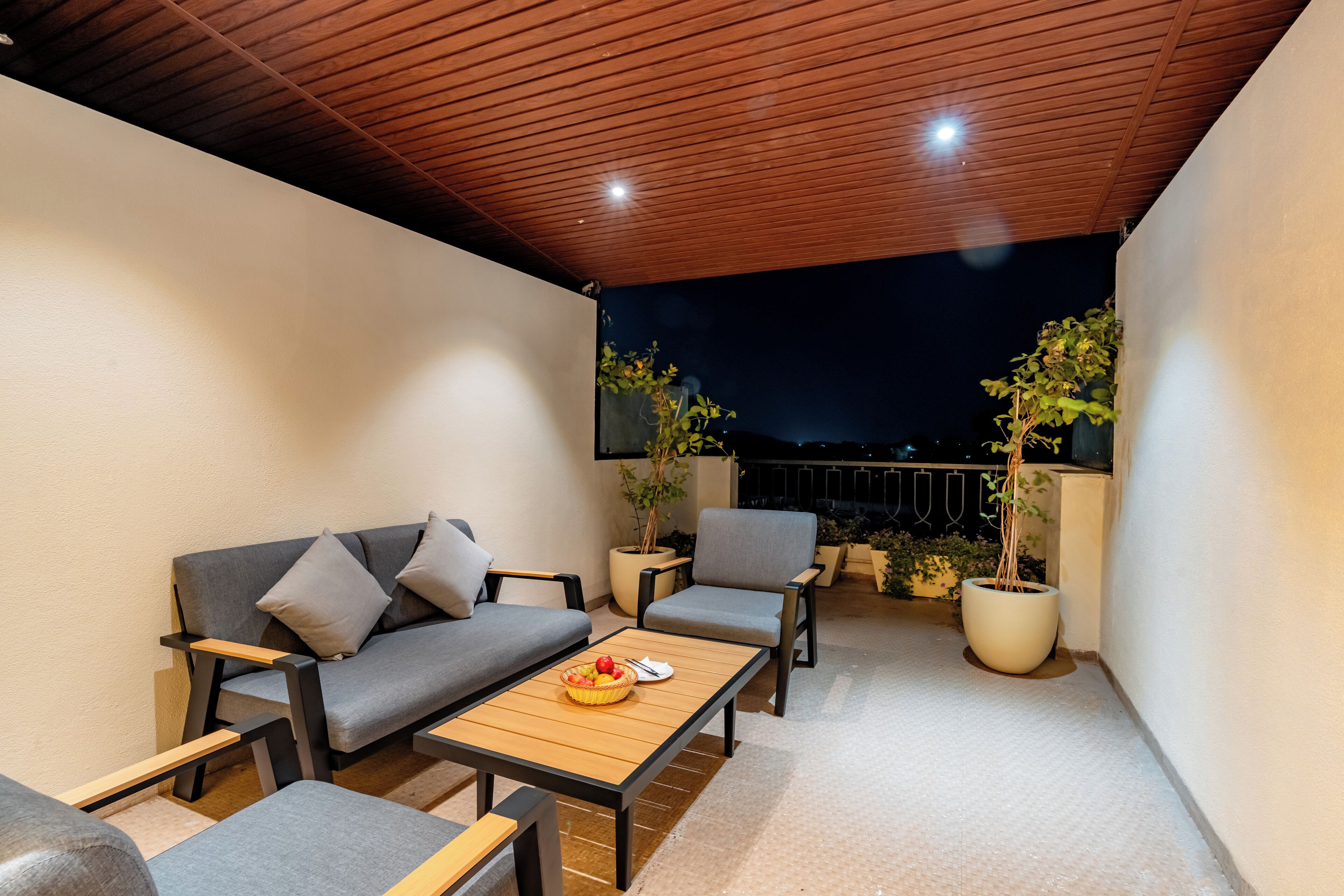 A covered outdoor seating area with a sofa, chairs, and a table.