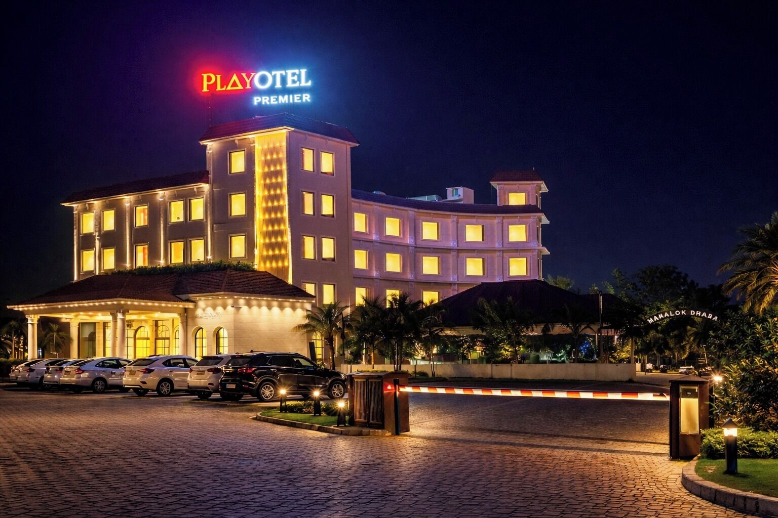 A Playotel Premier hotel with a multi-story building, a parking lot, and a gated entrance.