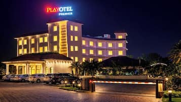 A Playotel Premier hotel with a multi-story building, a parking lot, and a gated entrance.