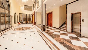 A spacious lobby with a checkered floor, a large chandelier, and an elevator. - Playotel Premier Ujjain (Ujjain)
