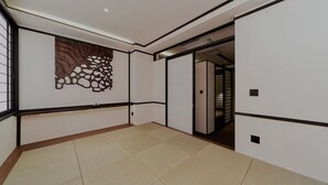 A room with a tiled floor, a decorative wall piece, and a sliding door leading to another room. - hokkawaakihabara (Tokyo)
