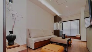 A modern living room with a sofa, ottoman, and a decorative vase. - hokkawaakihabara (Tokyo)