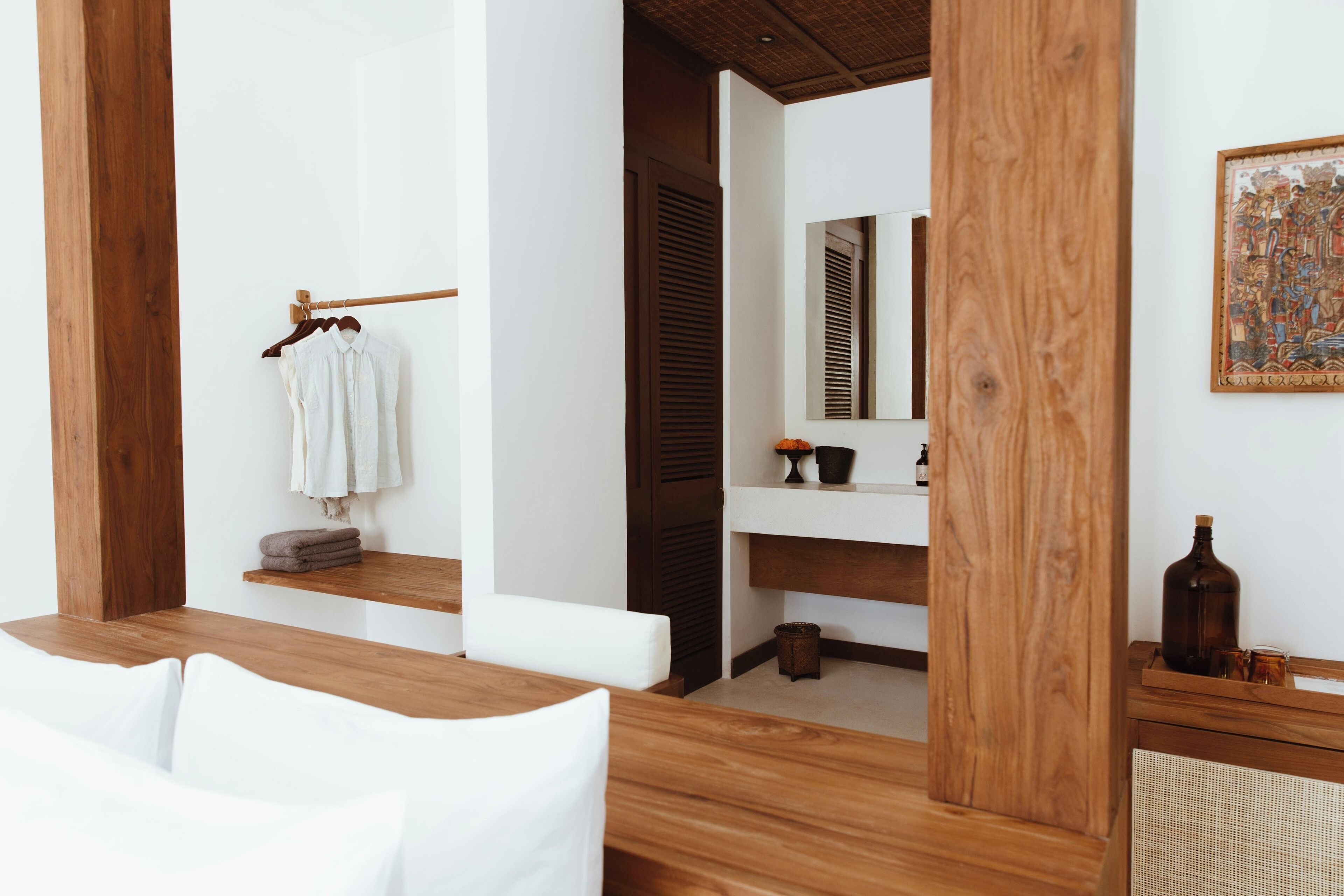 Un baño moderno con detalles de madera, un lavamanos blanco y un espejo.