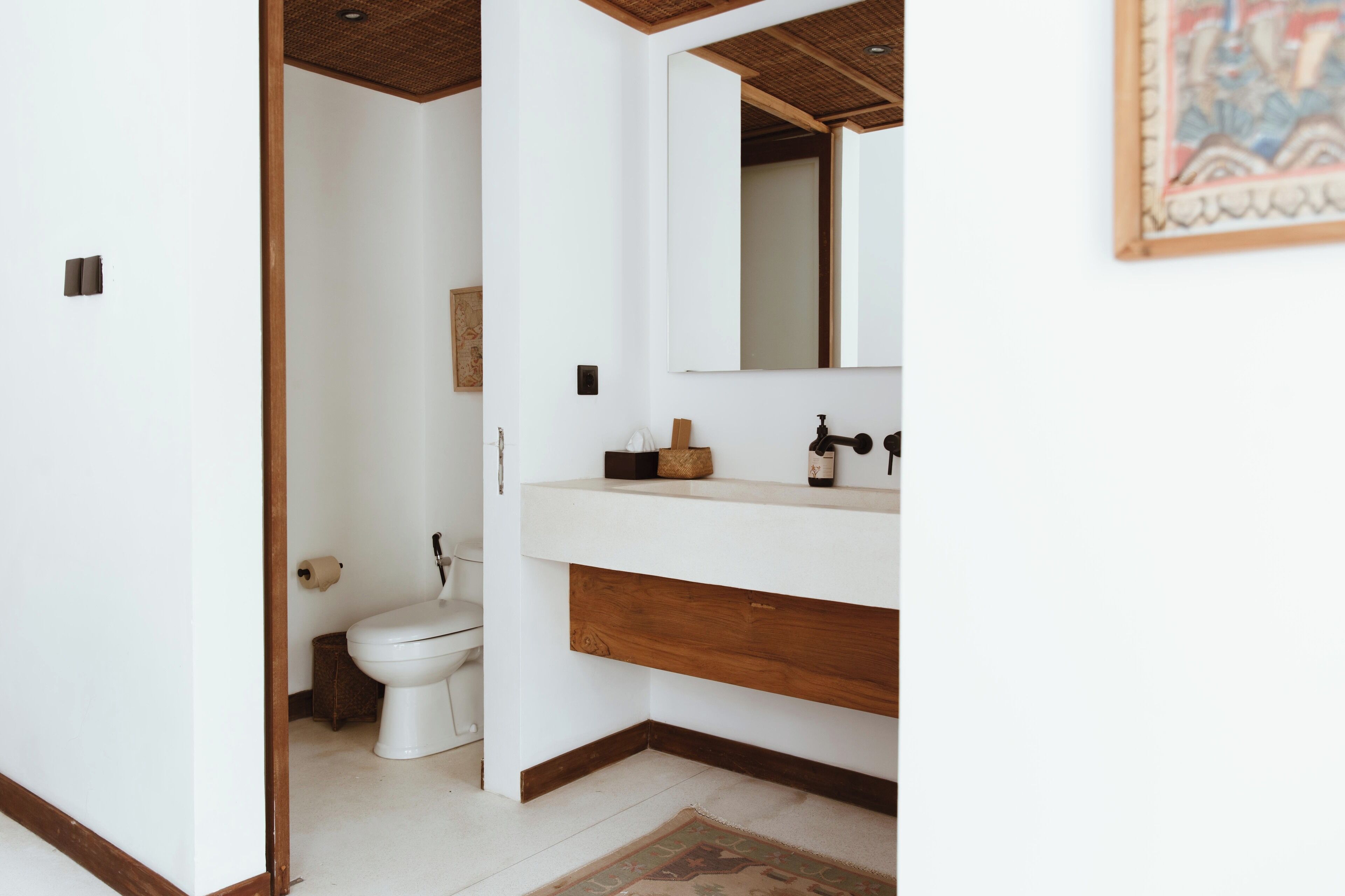 Une salle de bain moderne avec des toilettes blanches, un meuble-lavabo en bois et un grand miroir.