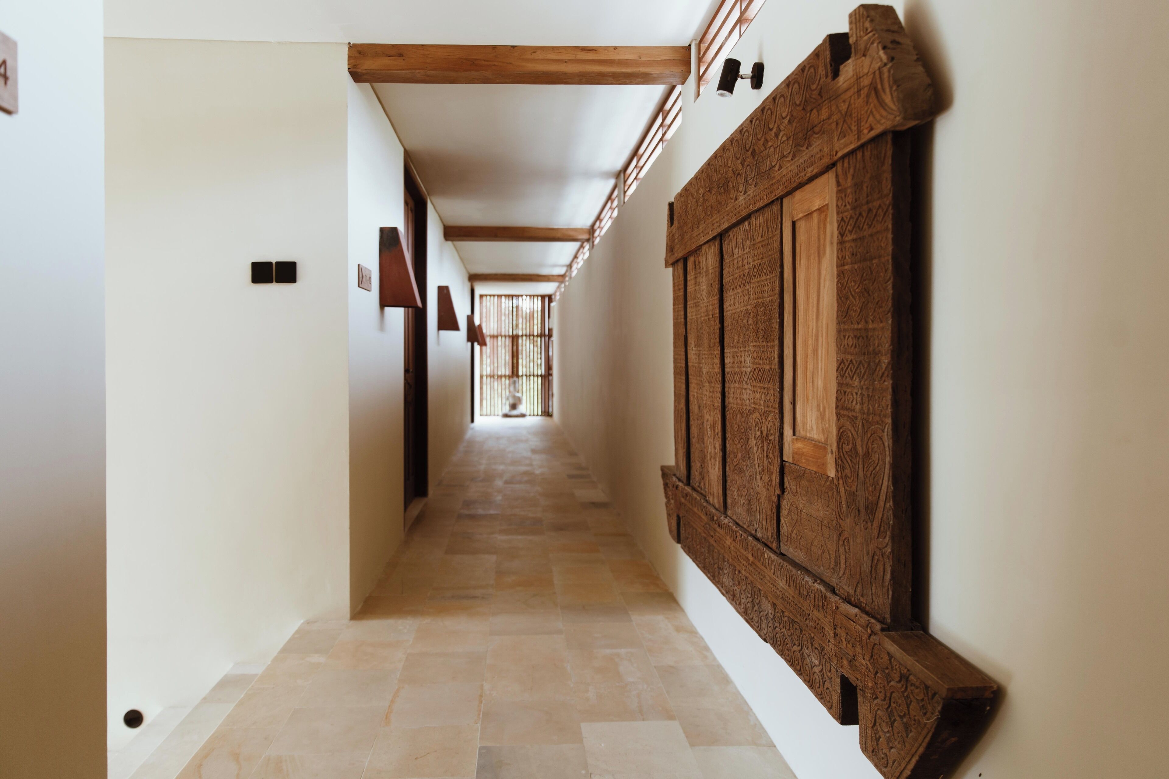 A hallway with a wooden panel wall, a tiled floor, and a door at the end.