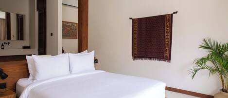 A neatly made bed with white linens, a wooden headboard, a wall-mounted tapestry, and a potted plant.