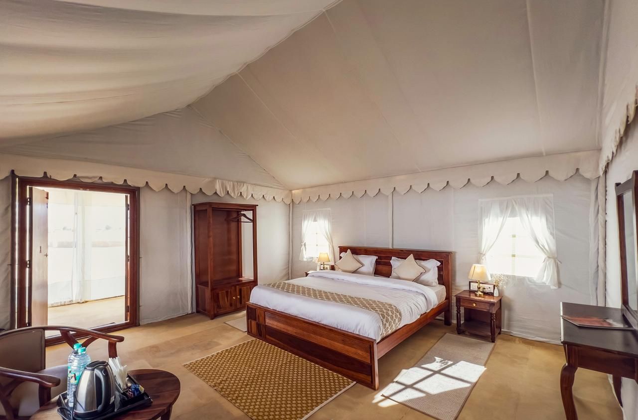 Una habitación amplia con carpa, una cama grande, un escritorio y una silla.