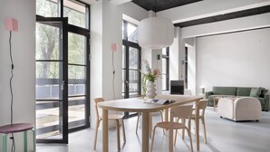 Une pièce moderne et bien éclairée, avec une grande table et des chaises, un canapé et un luminaire suspendu.