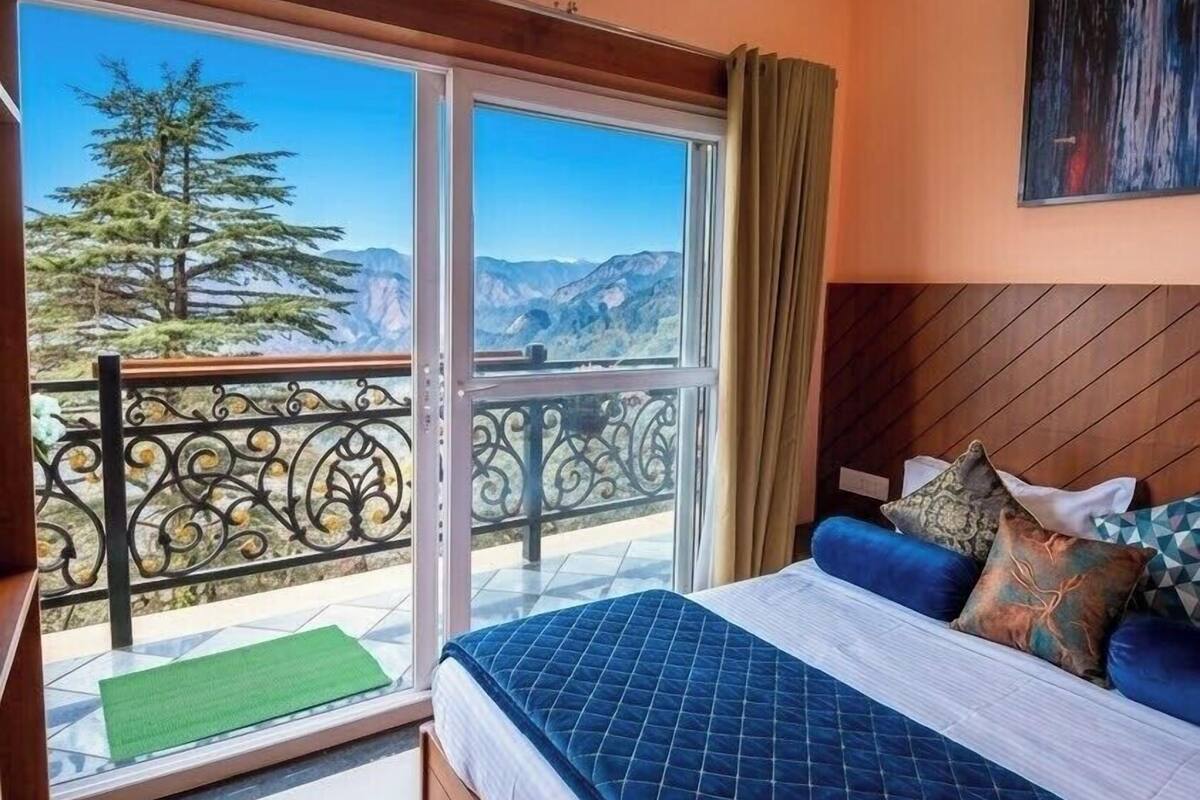 Una camera da letto con un letto, vista sulle montagne e un balcone con ringhiera.