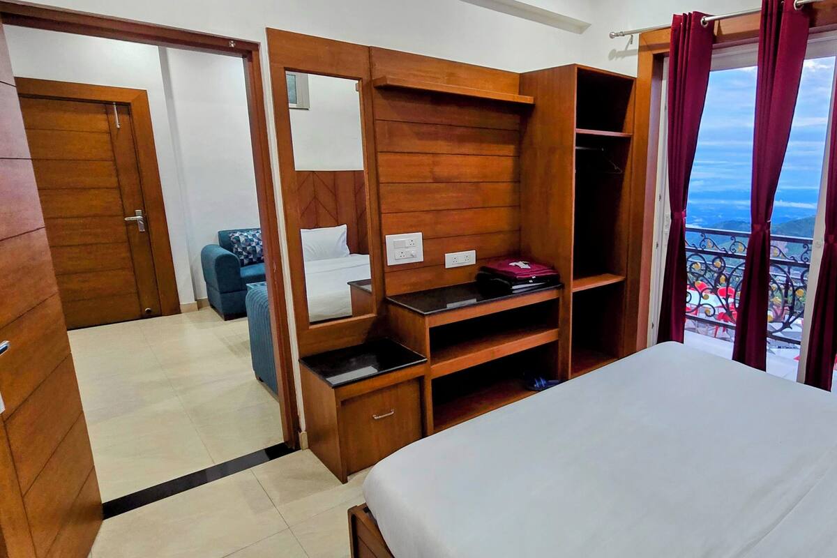 Una camera d'albergo con un letto, un armadio, una scrivania e vista sulle montagne.